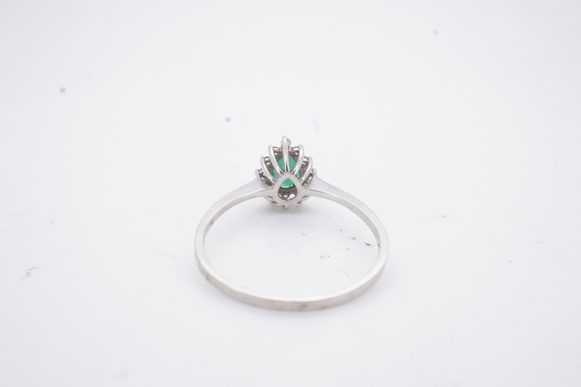 A modern white metal(stamped 14k), emerald and diamond set pear shaped cluster ring, size R, gross weight 1.3 grams.
